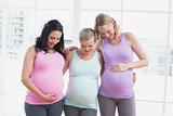 Pregnant women standing smiling at bumps