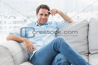 Smiling handsome man relaxing on the couch looking at camera