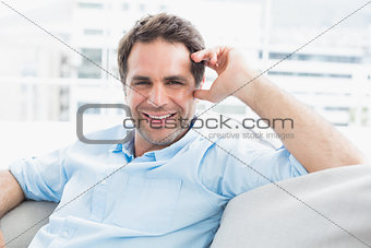Cheerful handsome man relaxing on the couch looking at camera
