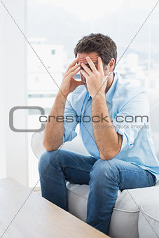 Man with headache sitting on the couch
