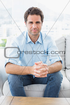 Handsome man sitting on the couch smiling at camera