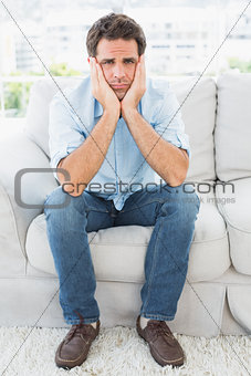 Upset man sitting on the couch looking at camera