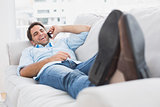 Happy man lying on the couch chatting on the phone