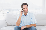 Happy man sitting on the couch chatting on the phone
