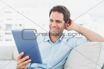 Handsome man sitting on the sofa using his tablet