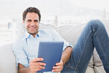 Happy man relaxing on the couch using his tablet