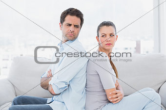 Angry couple sitting back to back on the couch