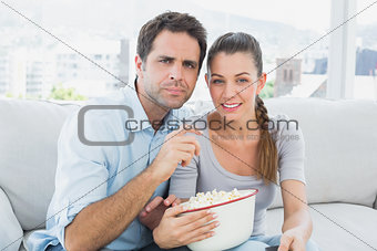 Couple watching movie on the sofa with bowl of popcorn