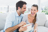 Couple watching funny movie on the sofa with bowl of popcorn