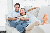 Couple watching funny movie lying on the sofa with bowl of popcorn