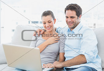 Cute couple sitting on the couch using laptop together