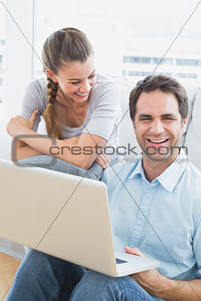 Happy couple sitting on the sofa using laptop