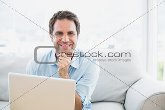 Happy man using laptop smiling at camera