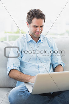 Content man using laptop sitting on sofa