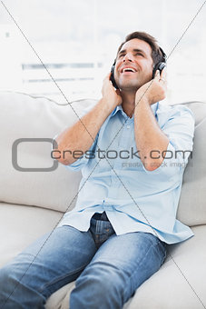 Happy man sitting on sofa listening to music