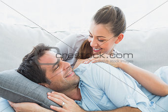 Cheerful couple relaxing on their sofa smiling at each other