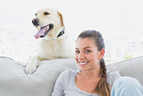 Happy woman posing with her yellow labrador on the couch