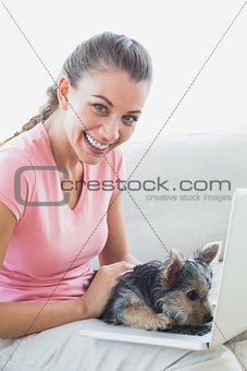 Smiling woman using laptop with her yorkshire terrier
