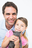 Cute father and daughter with pet kitten smiling at camera together