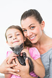 Smiling mother and daughter sitting with pet kitten together