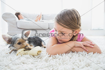 Little girl lying on rug with yorkshire terrier