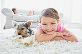 Little girl lying on rug with yorkshire terrier smiling at camera