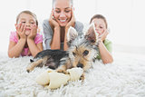 Siblings lying on rug looking at their yorkshire terrier with mother