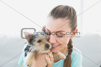 Smiling woman cuddling her yorkshire terrier puppy