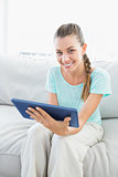 Smiling woman sitting on couch using tablet pc