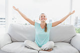 Cheerful woman sitting on couch with arms outstretched