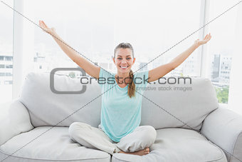 Smiling woman sitting on couch with arms outstretched