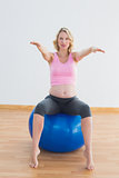Pretty blonde pregnant woman sitting on exercise ball