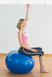 Happy blonde pregnant woman exercising on exercise ball