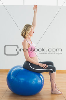 Happy blonde pregnant woman exercising on exercise ball