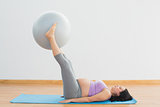 Happy pregnant woman lifting exercise ball with legs