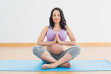 Pregnant woman sitting on mat in lotus pose