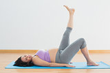 Pregnant woman lying on mat lifting her leg