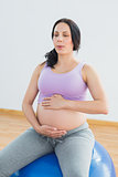Pregnant brunette sitting on exercise ball breathing