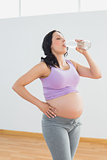 Pregnant woman drinking from bottle of water