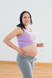 Pregnant woman holding bottle of water smiling at camera