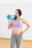 Happy pregnant woman holding exercise mat
