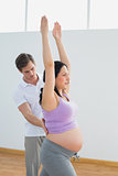 Breathing pregnant woman doing yoga with a personal trainer