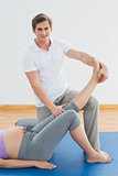 Personal trainer lifting pregnant clients leg