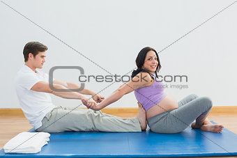 Masseur stretching pregnant womans arms and shoulders