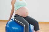 Pregnant woman sitting on blue exercise ball