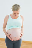 Blonde pregnant woman looking down at her belly