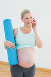 Happy pregnant woman holding exercise mat on the phone