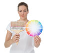 Young woman looking at paint samples and paintbrush