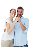 Portrait of cheerful couple singing into microphone