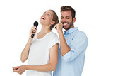 Cheerful couple singing into microphones